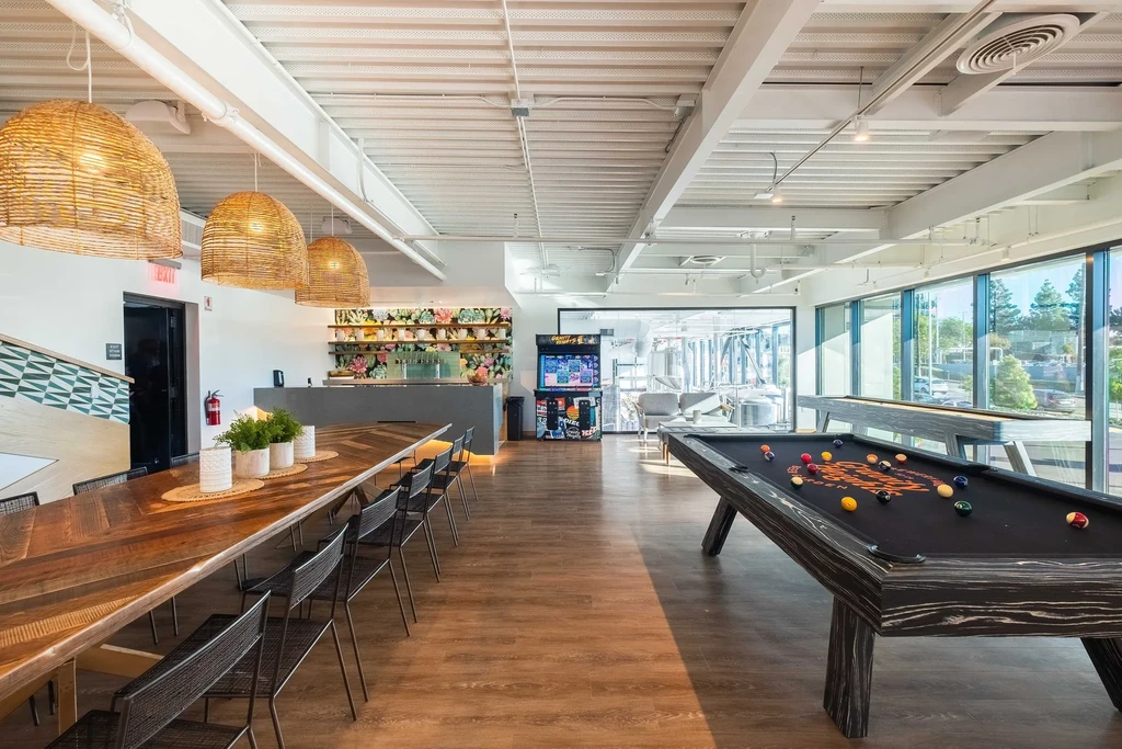 Modern industrial brewery taproom interior with games and brewing tanks.