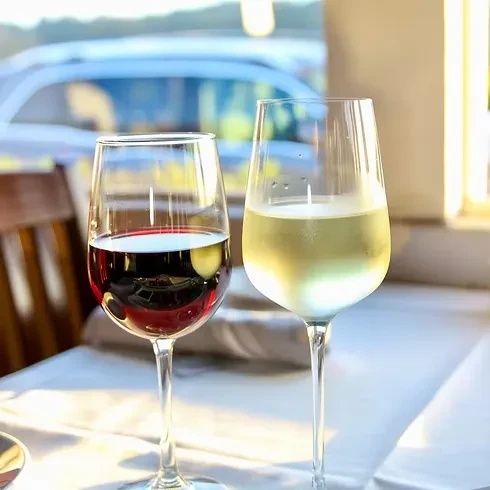 Red and white wine in glasses on a white tablecloth.