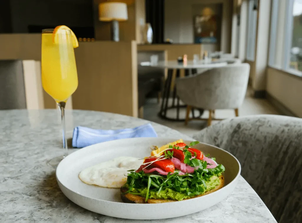 Avocado toast with eggs, pickled onions, arugula, and a mimosa.