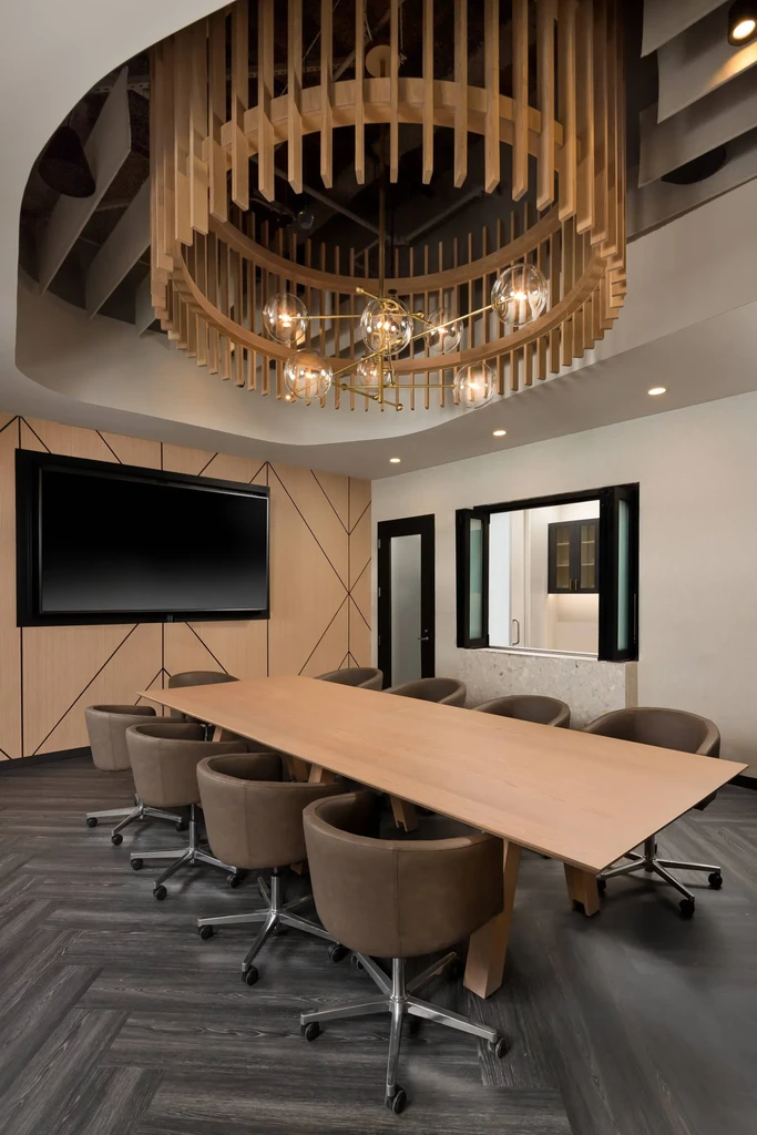 Modern private dining room with circular wood slat chandelier, table, chairs.
