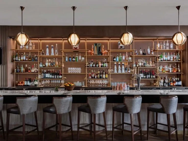 Upscale, well-stocked bar interior with marble counter and brass shelving.