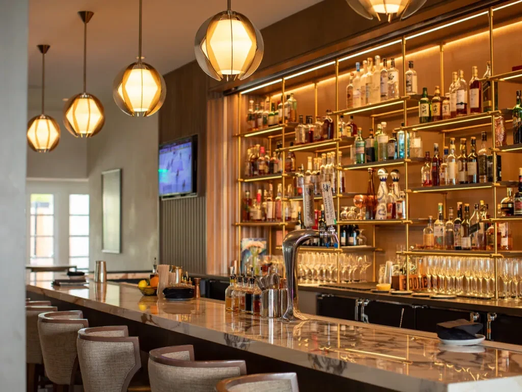 Elegant bar with marble counter, backlit liquor shelves, beer taps, and TV.