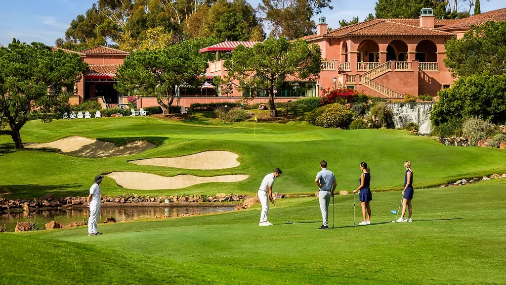 Golf course with Mediterranean building, waterfall, and five golfers.