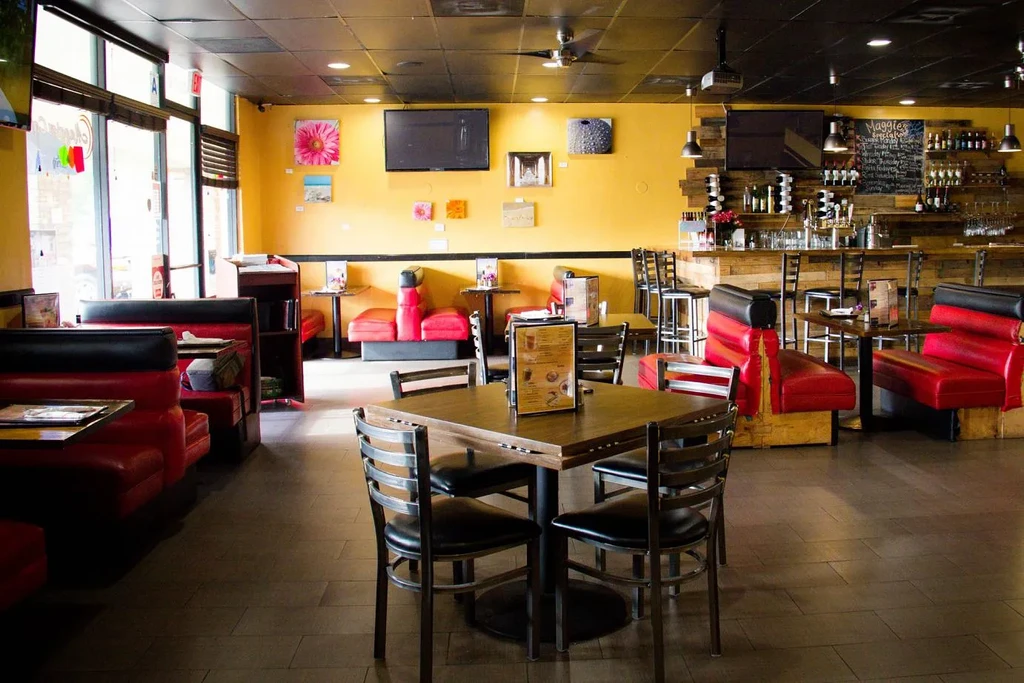 Empty casual restaurant interior with yellow walls, red booths, and rustic bar.