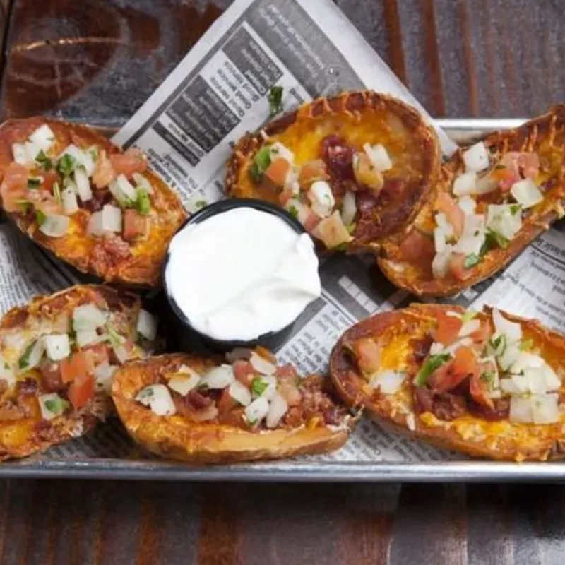 Six potato skins filled with cheese, bacon, tomato, herbs, and dip.