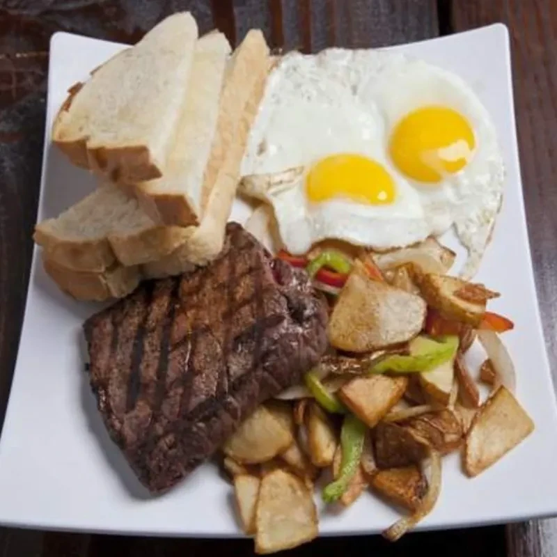 Overhead shot of grilled steak, sunny-side eggs, potatoes, and toast.