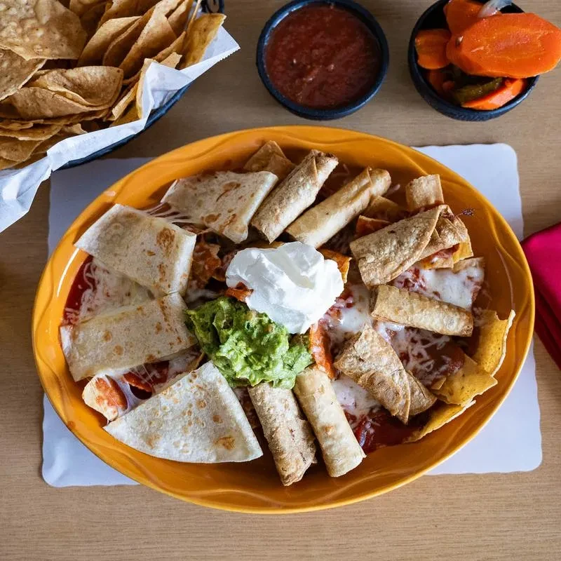 Overhead view: loaded nachos, taquitos, quesadillas, guacamole, and salsa.