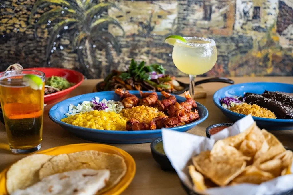 Vibrant spread of Mexican food and drinks on a restaurant table.