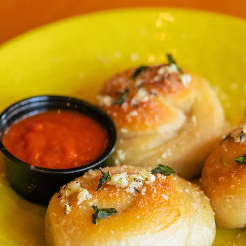 Three savory rolls with garlic, herbs, Parmesan, and marinara dip.