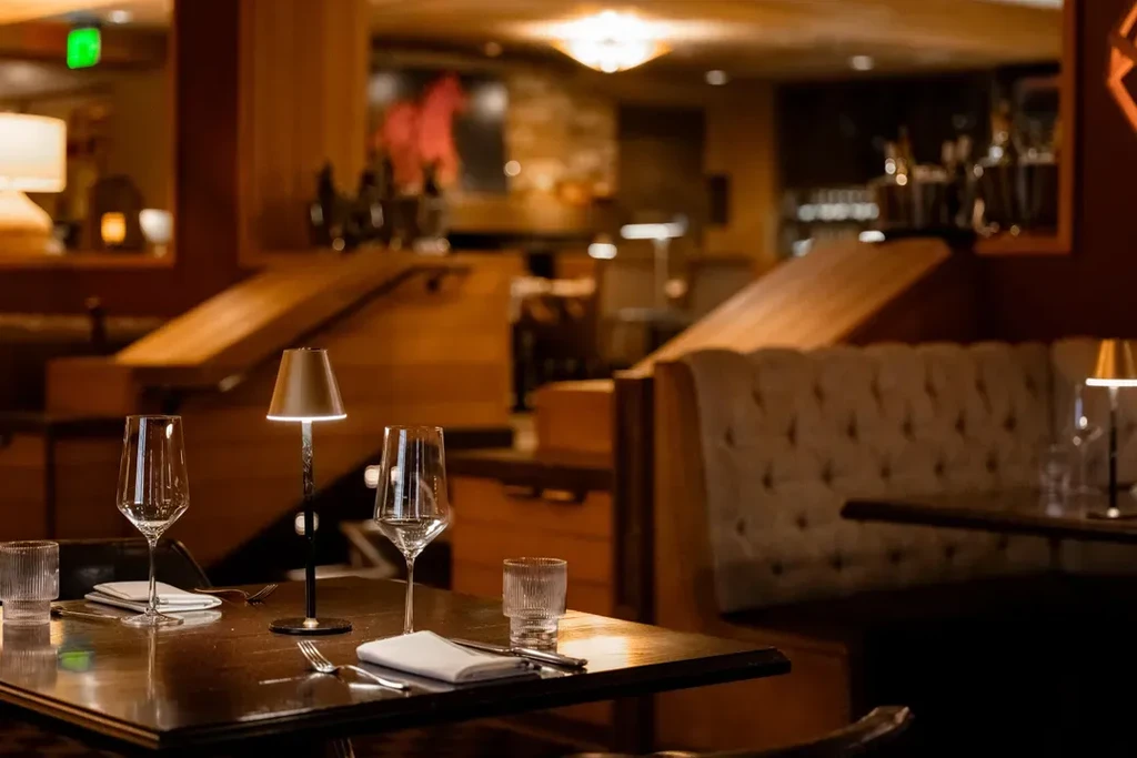 Warmly lit upscale restaurant table set for two with wine glasses.