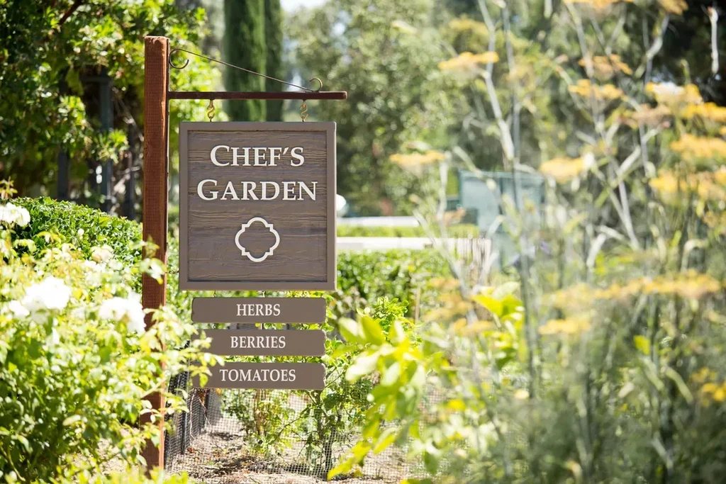 Rustic wooden "CHEF'S GARDEN" sign with "HERBS, BERRIES, TOMATOES" plaques.