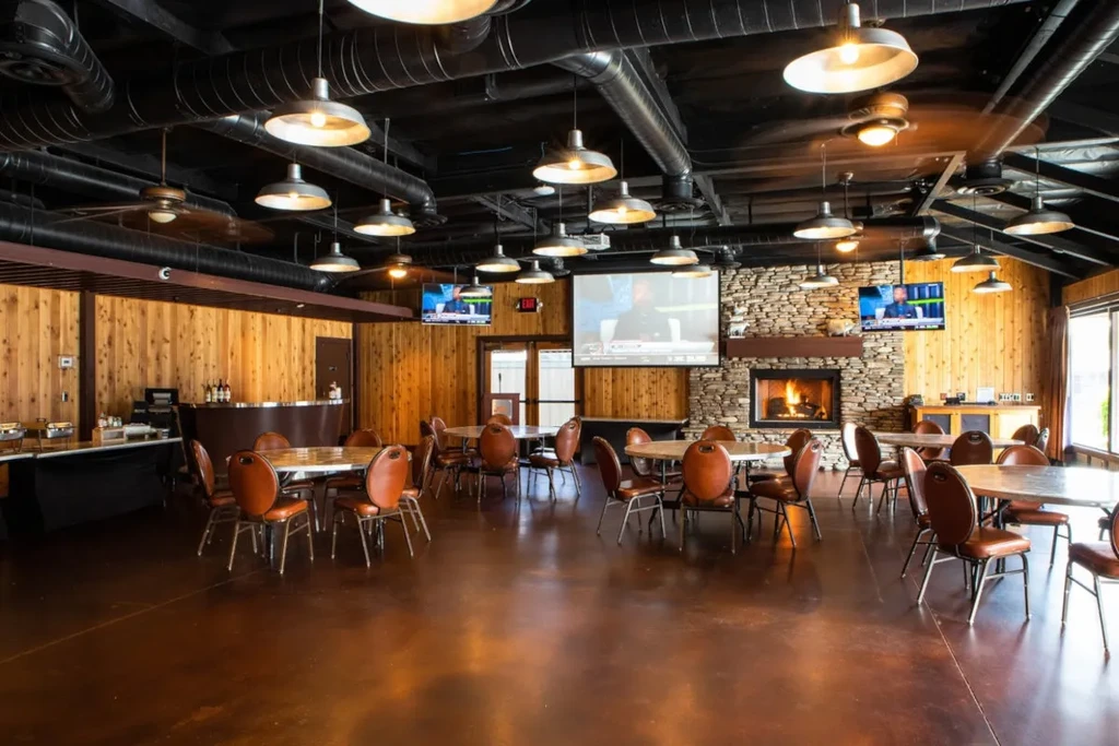 Rustic-industrial restaurant dining area with a bar, fireplace, and TVs.