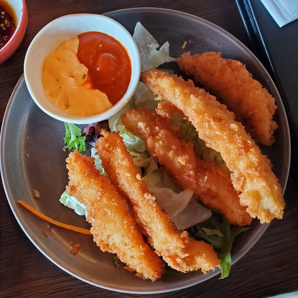 Overhead: Fried breaded strips on lettuce with two distinct dipping sauces.