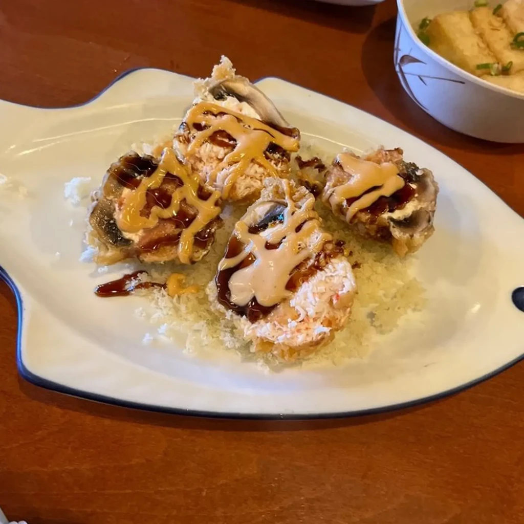 Fried sushi rolls on fish-shaped plate with two sauces and soup.
