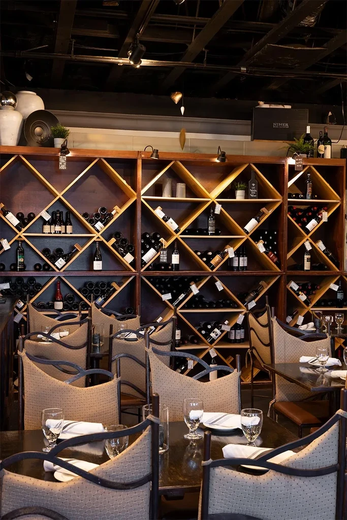 Large wine rack filled with bottles in an empty restaurant interior.