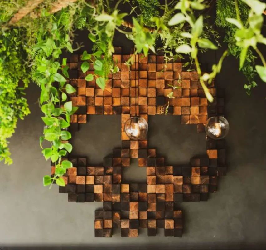 Pixelated wooden skull wall art with glowing eyes and cascading plants.