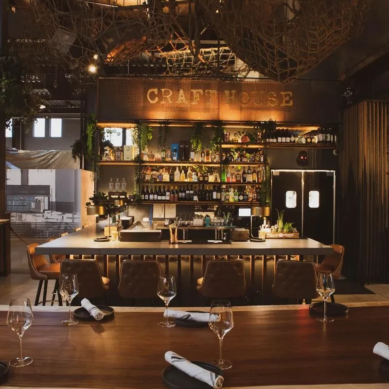 Empty, sophisticated bar with stocked shelves and a set communal table.
