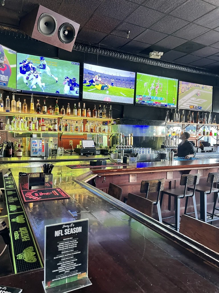 Sports bar: illuminated liquor bottles, multiple TVs showing football games.