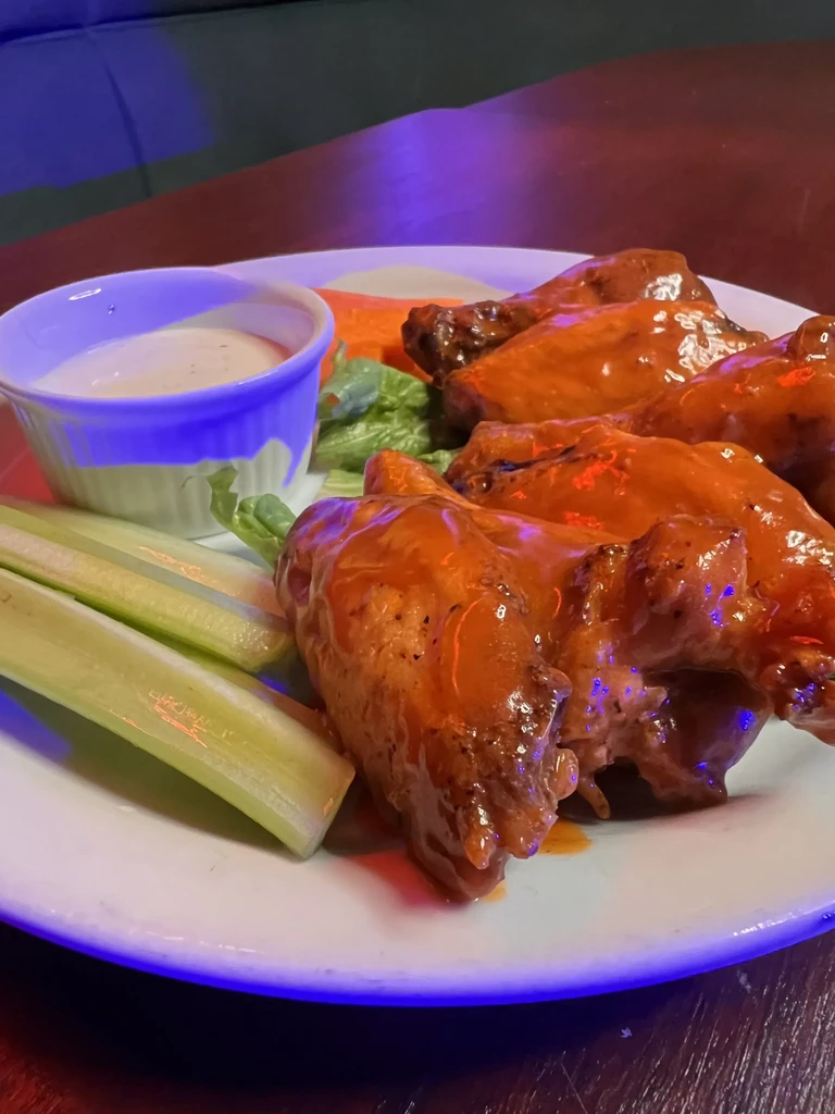 Plate of buffalo chicken wings, celery, carrots, creamy dipping sauce.