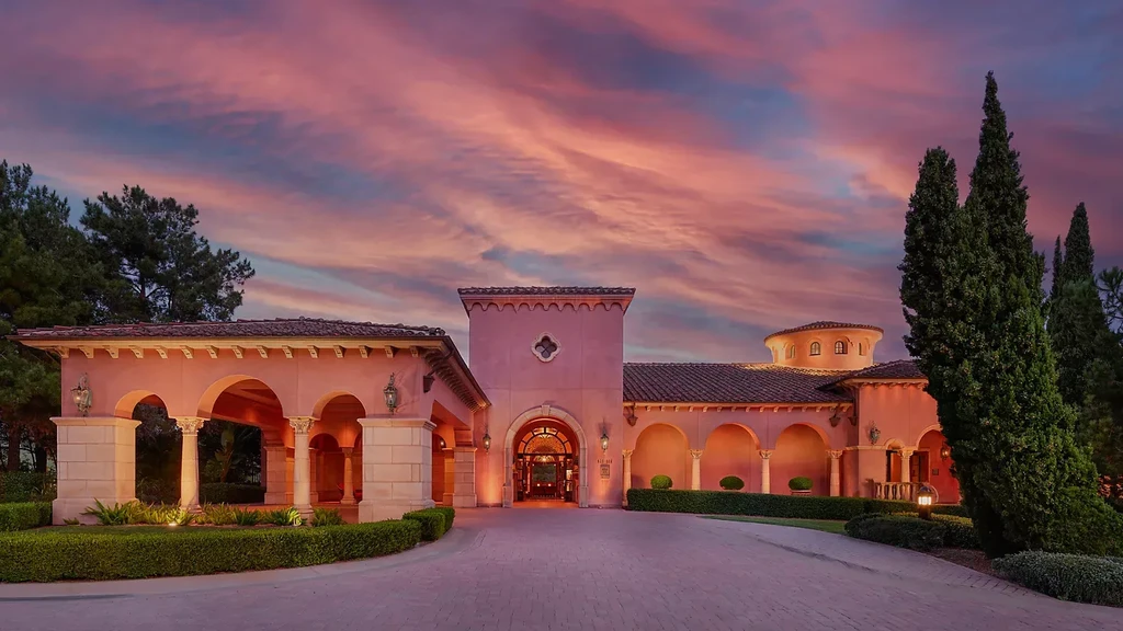Mediterranean resort exterior with arched entrance and red tile roofs at dusk.
