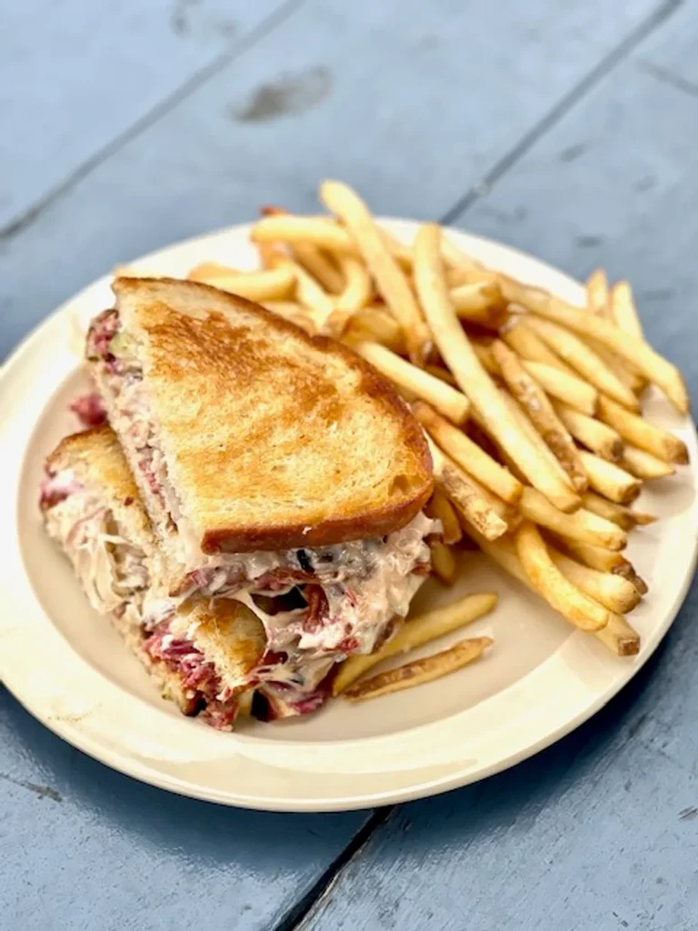 Grilled sandwich with melted cheese, meat, and french fries.
