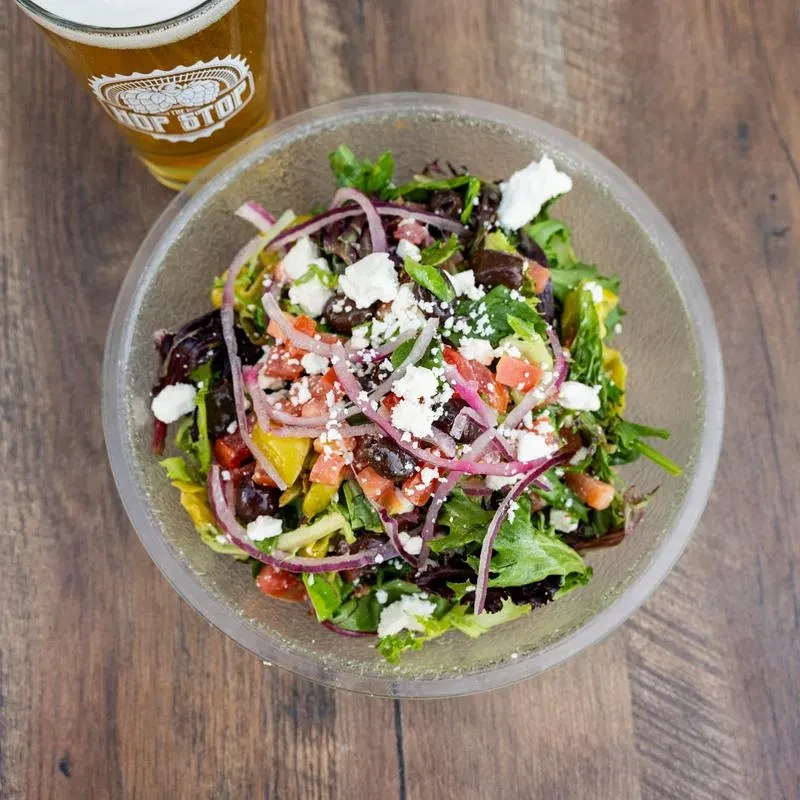 Colorful mixed salad with feta cheese and beer on a wooden table.
