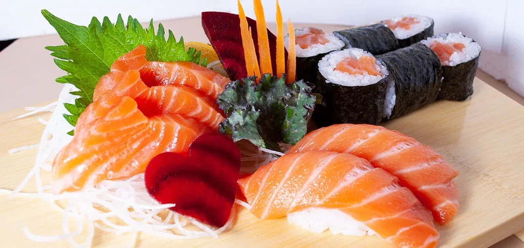 Assortment of fresh salmon sushi and sashimi on a wooden board.