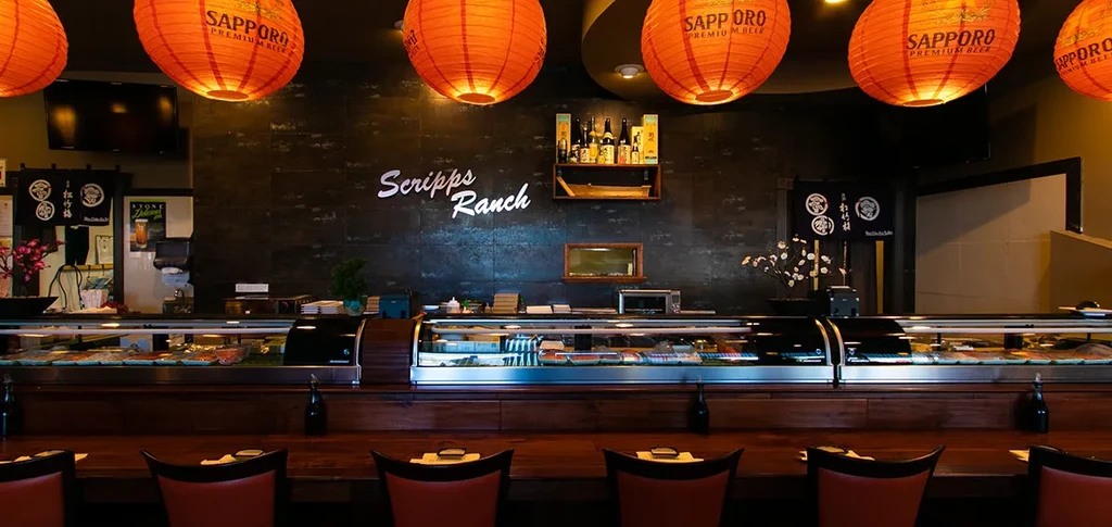 Sushi bar interior with counter, Scripps Ranch sign, Sapporo lanterns.