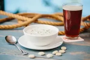 Creamy soup and amber beer on a rustic blue wooden table.