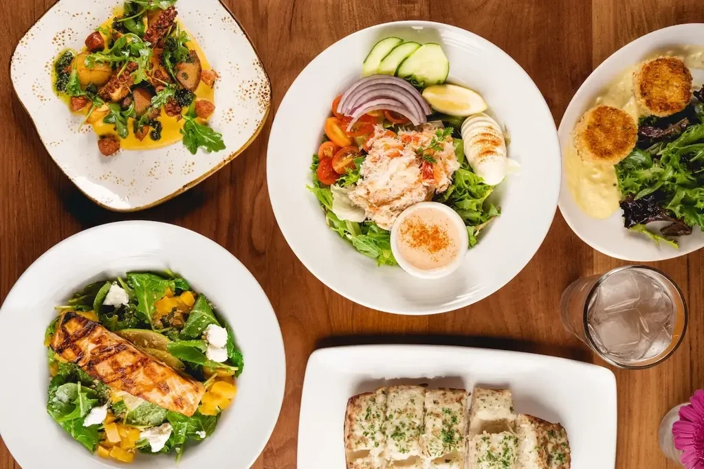 Overhead shot of diverse, well-plated dishes on a wooden table.