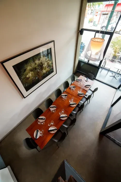 Modern restaurant interior with long wooden dining table set for guests.