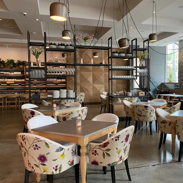 Modern restaurant dining area with patterned chairs and a large wine wall.