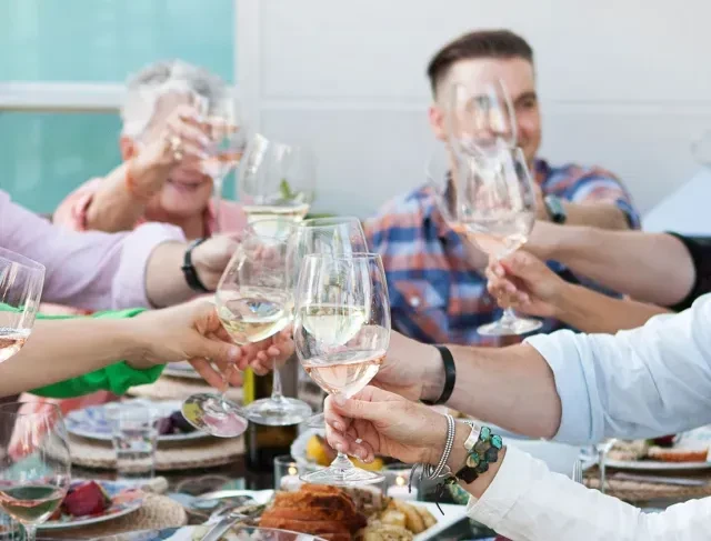 Group of people toasting with white and rosé wine.