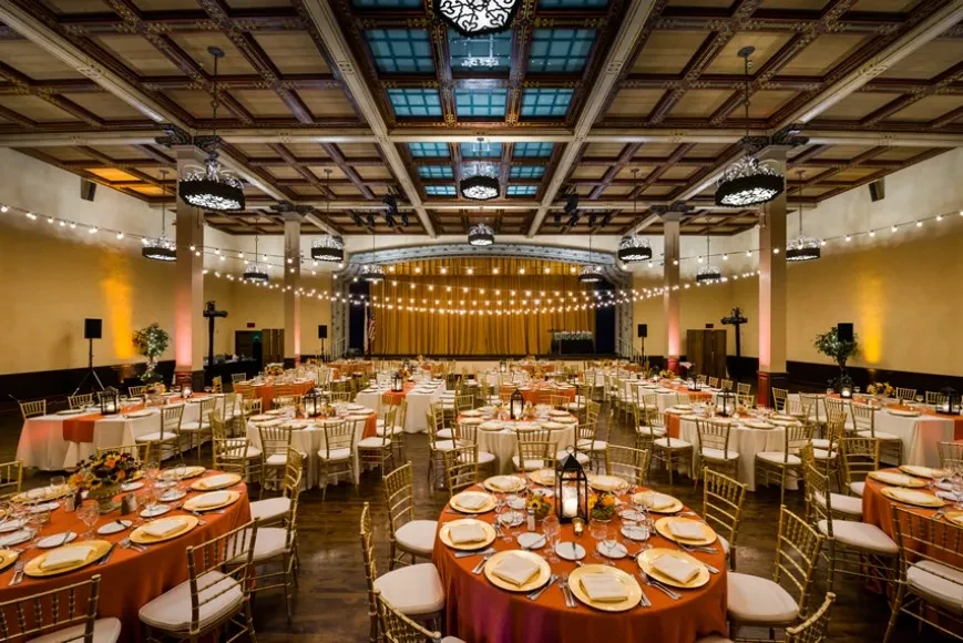 Elegant banquet hall with formally set tables, string lights, and ornate ceiling.