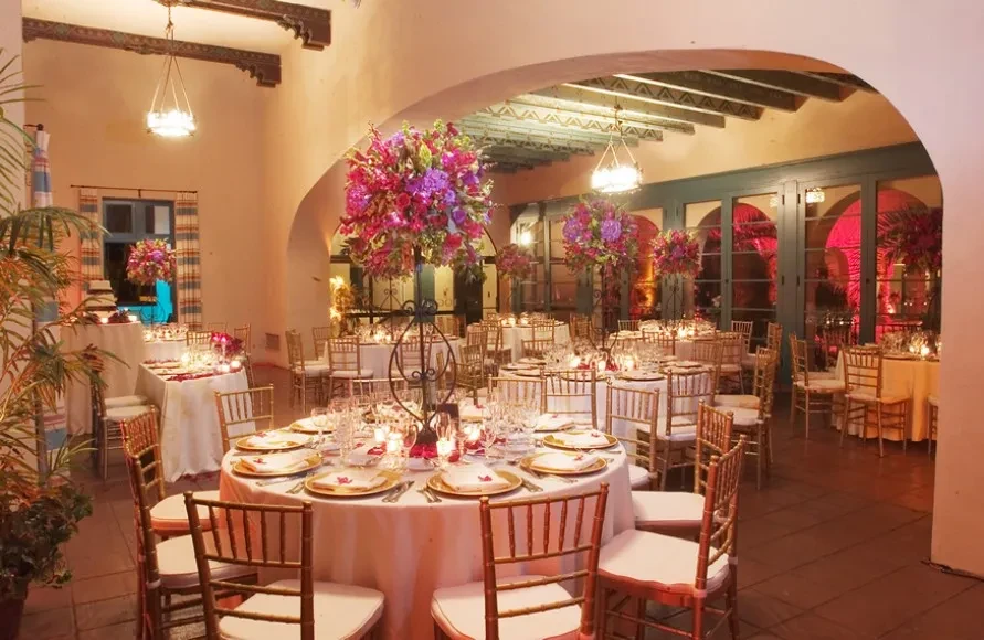 Elegant event space with floral centerpieces, gold chairs, and archways.