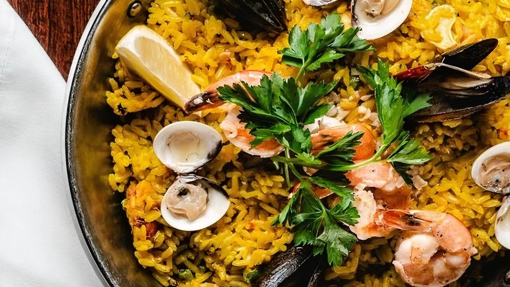 Close-up of vibrant seafood paella with shrimp, mussels, clams, and lemon.