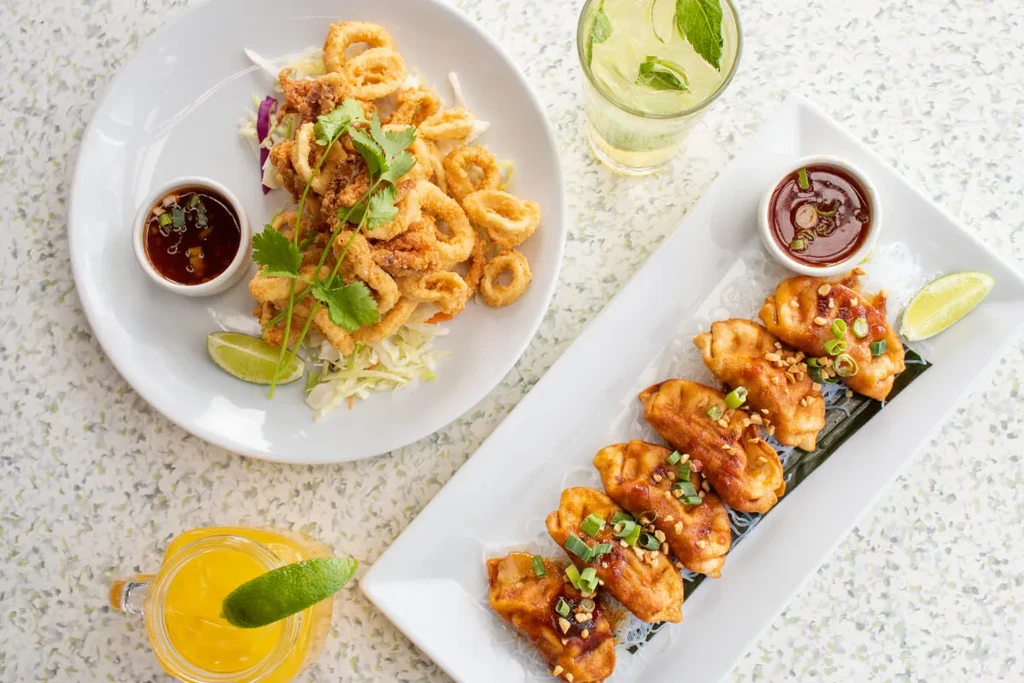 Overhead shot: fried calamari, pan-fried dumplings, two beverages.
