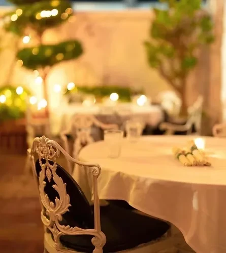 Upscale outdoor dining with an ornate chair and warm, blurred lights.
