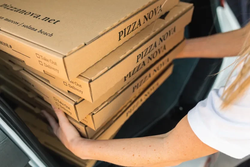 Person loads Pizza Nova pizza boxes from a car.