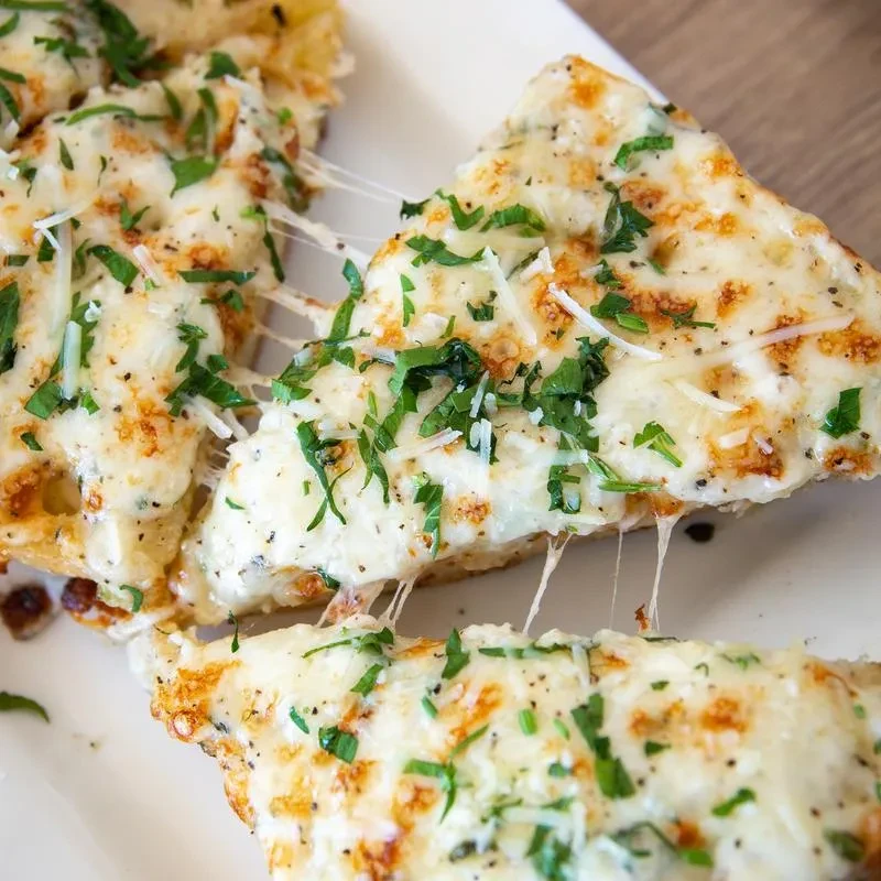Triangular cheesy bread slices with melted cheese, green herbs, cheese pull.