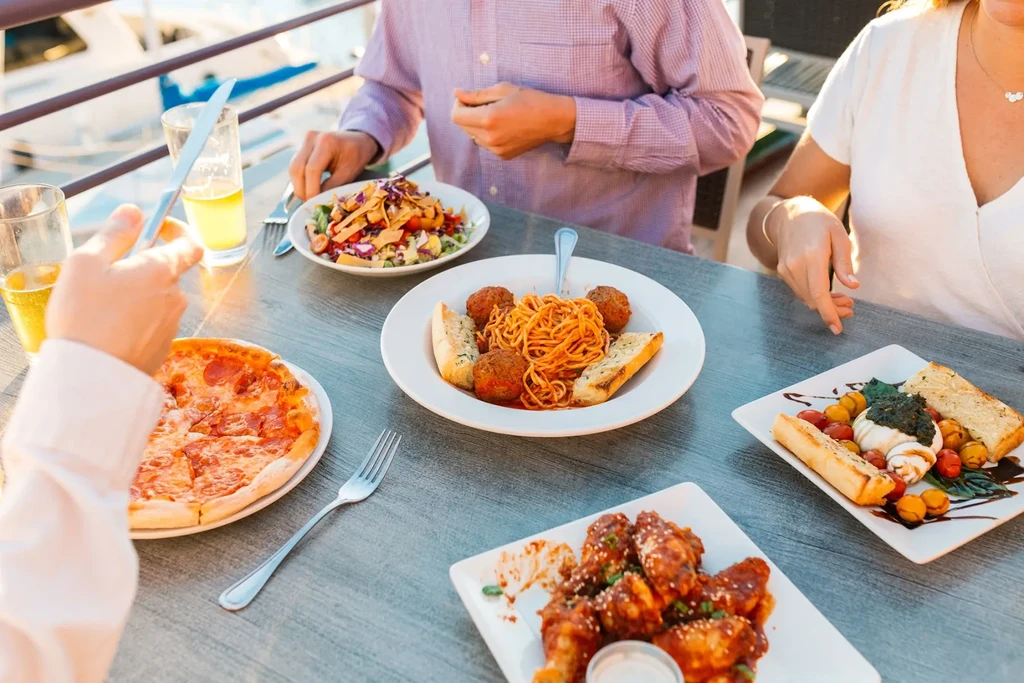 Overhead shot: People share diverse food and drinks at an outdoor table.
