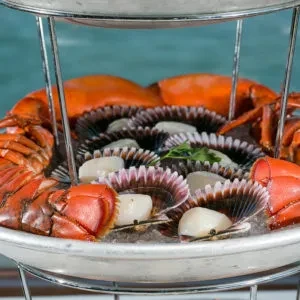 Tiered seafood tower with cooked lobster and scallops on ice.