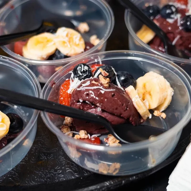 Multiple açai bowls topped with bananas, blueberries, strawberries, granola, coconut.