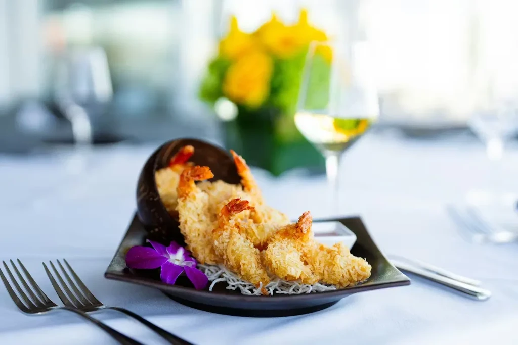 Golden fried shrimp, purple orchid garnish, dipping sauce, and white wine.
