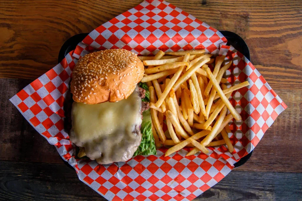 Top-down cheeseburger with melted cheese, fries in a checkered basket.