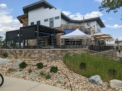 Modern commercial building featuring stone facade and diverse outdoor seating.