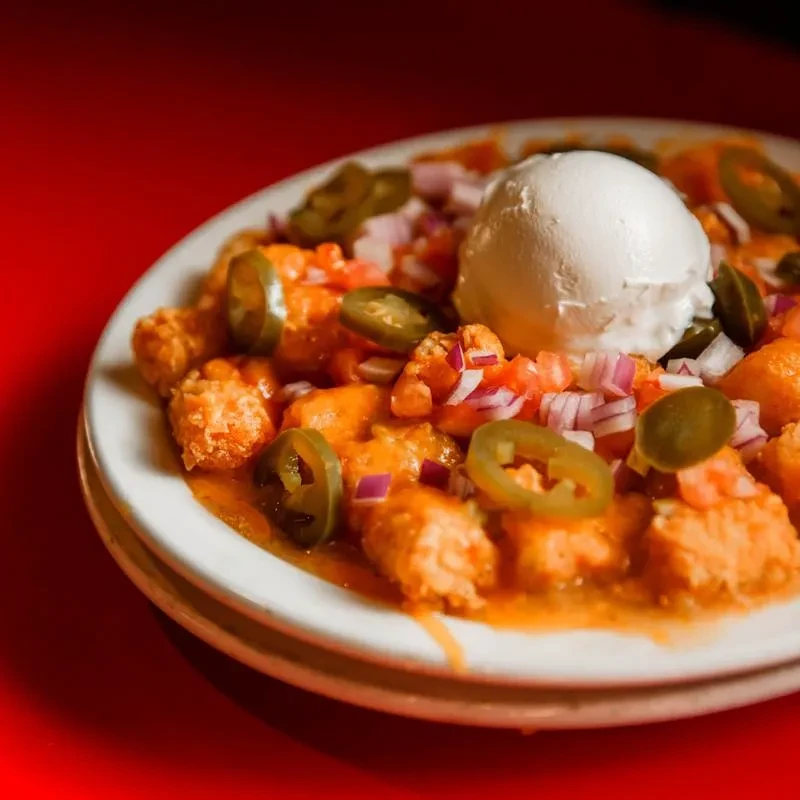 Loaded tater tots with cheese sauce, pico de gallo, jalapeños, sour cream.