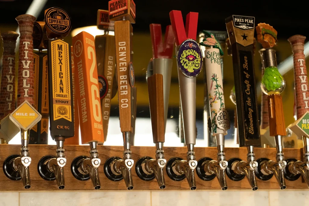 Multiple distinct beer tap handles displaying various brewery names and designs.