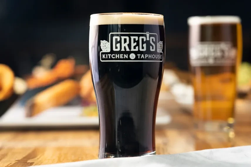 Dark beer in a branded Greg's Kitchen & Taphouse glass.