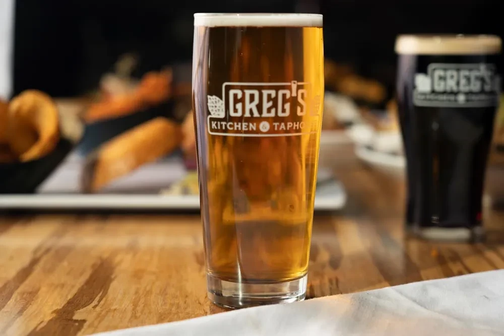 Greg's branded light and dark beers, food on wooden table.